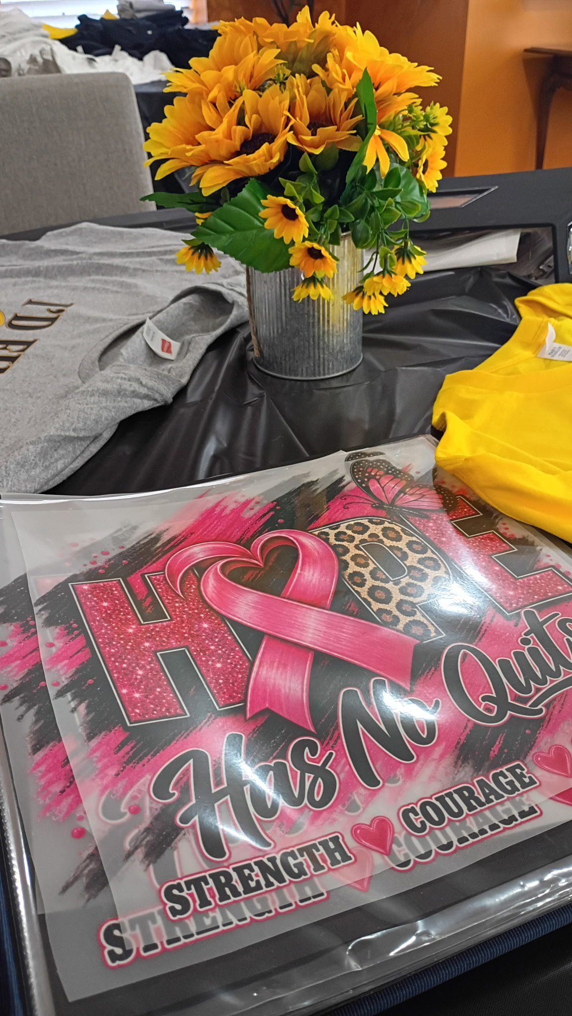 Shirt designs and event supplies displayed with sunflower decor